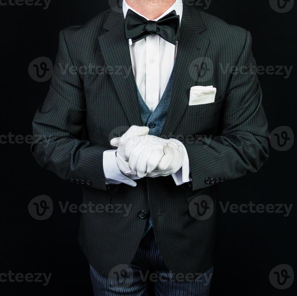 retrato de mayordomo con traje oscuro y guantes blancos ansiosos por servir. concepto de industria de servicios y hospitalidad profesional. foto