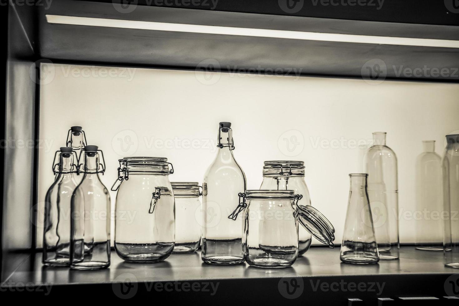 una exhibición de objetos de vidrio, grupo de botellas y frascos en blanco y negro foto