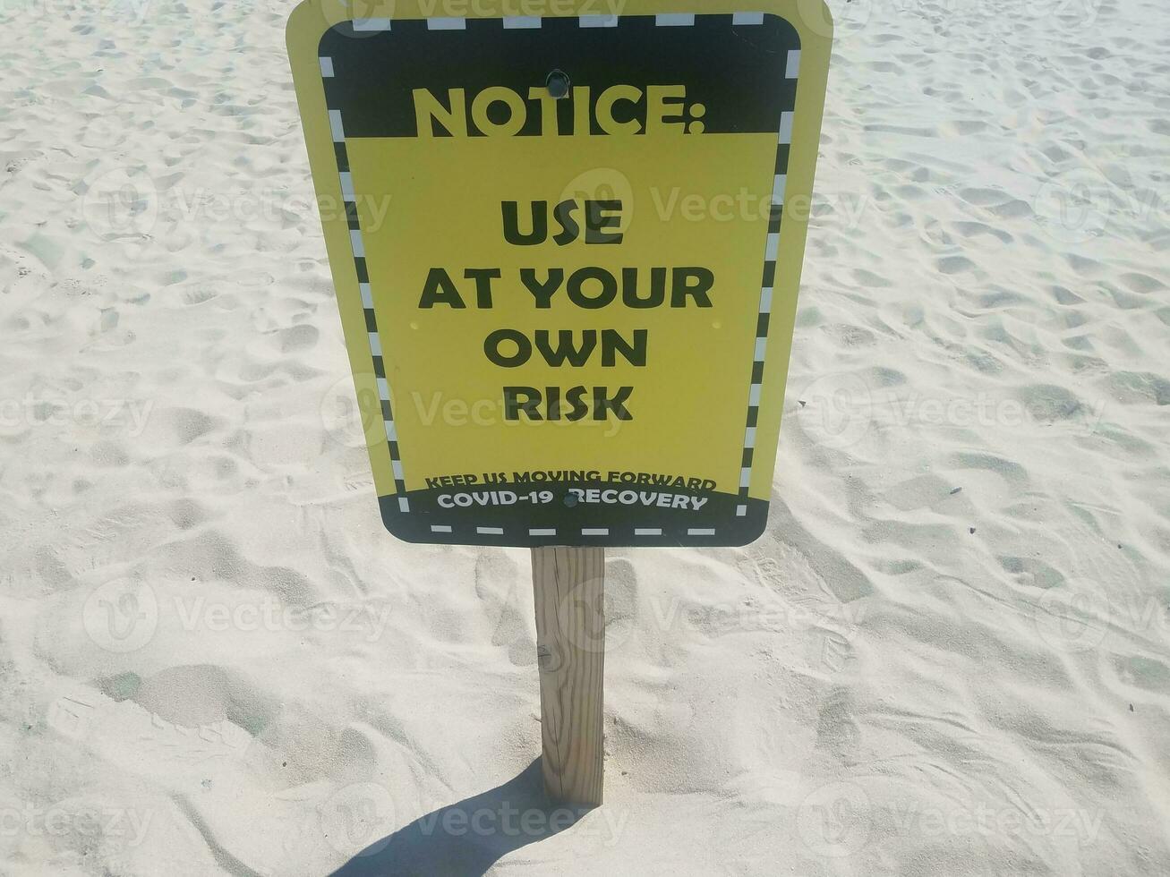 notice use at your own risk covid 19 sign on beach photo