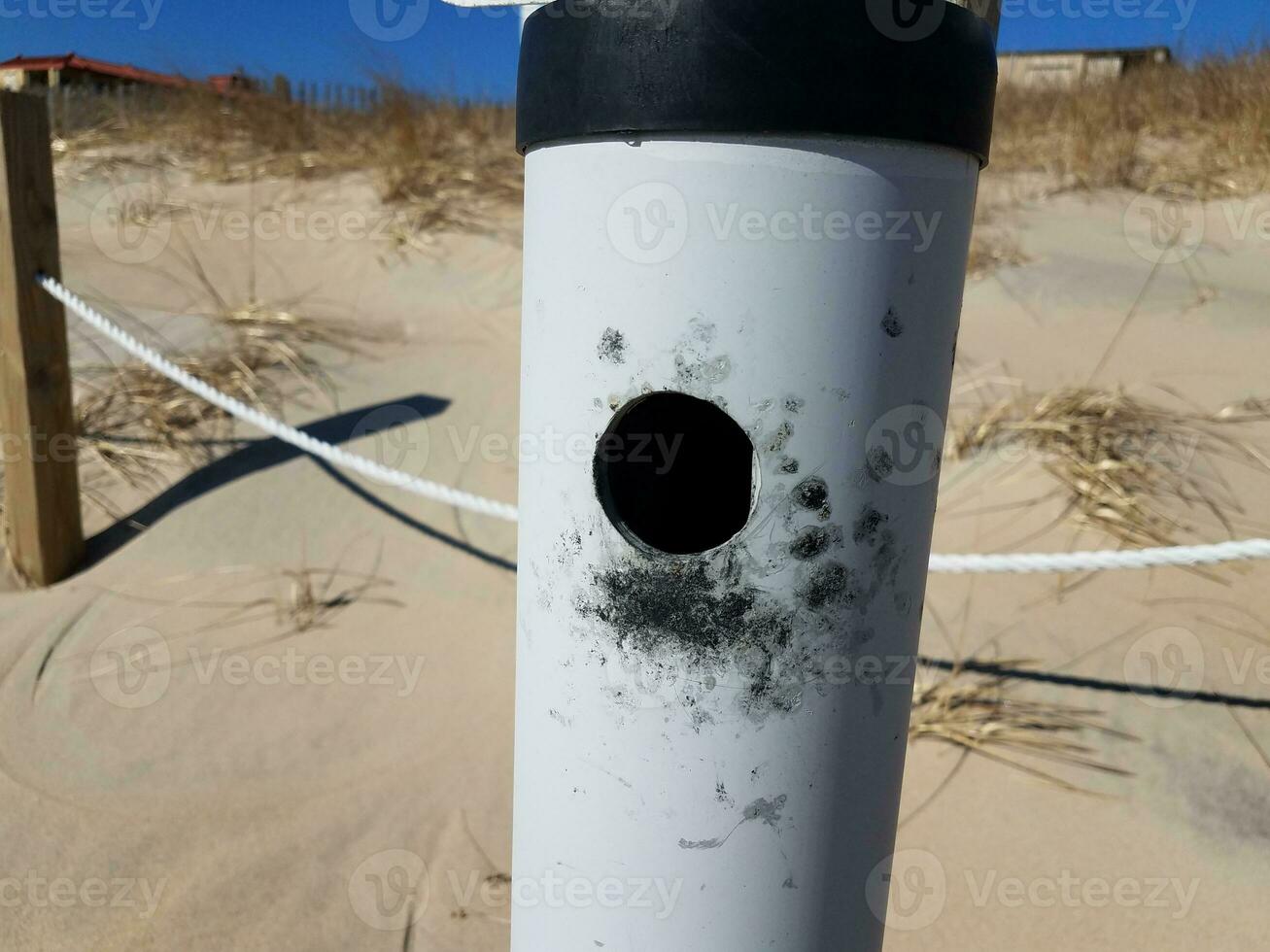 metallic cigarette smoking trash can at beach with sand photo