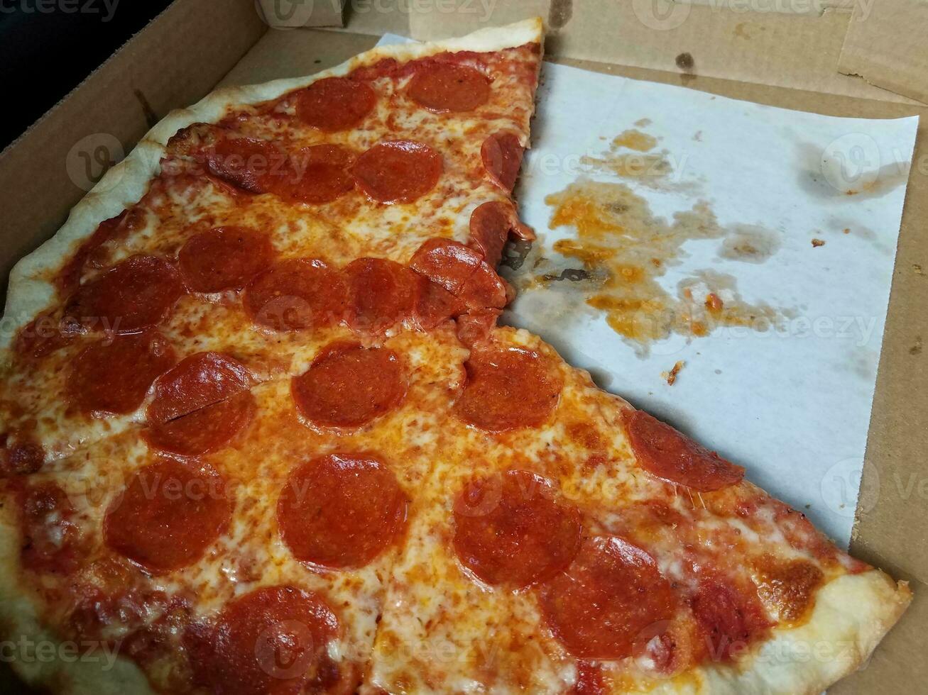 greasy pepperoni and cheese pizza in cardboard box photo