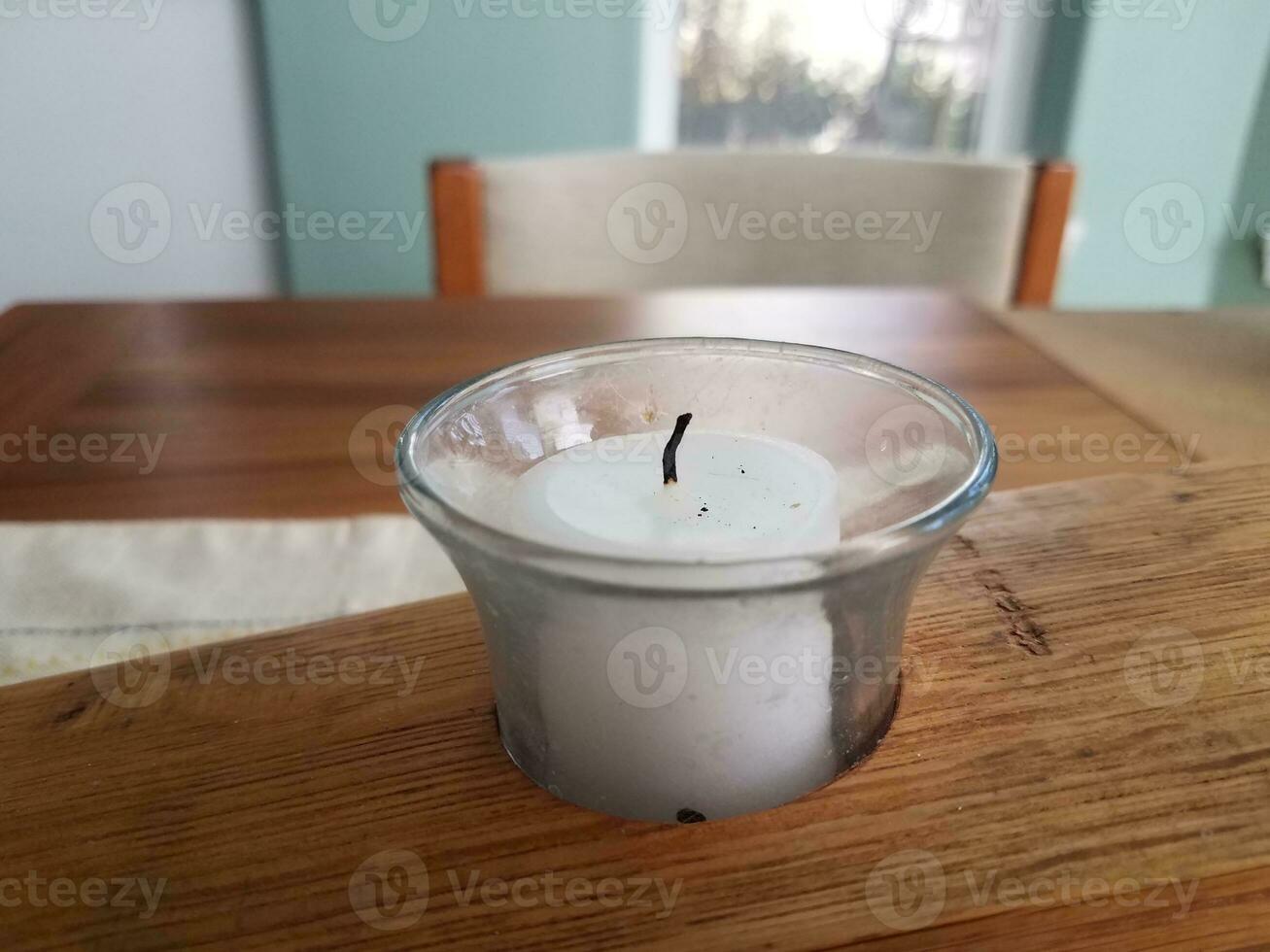 white candle in a wooden holder on a table photo