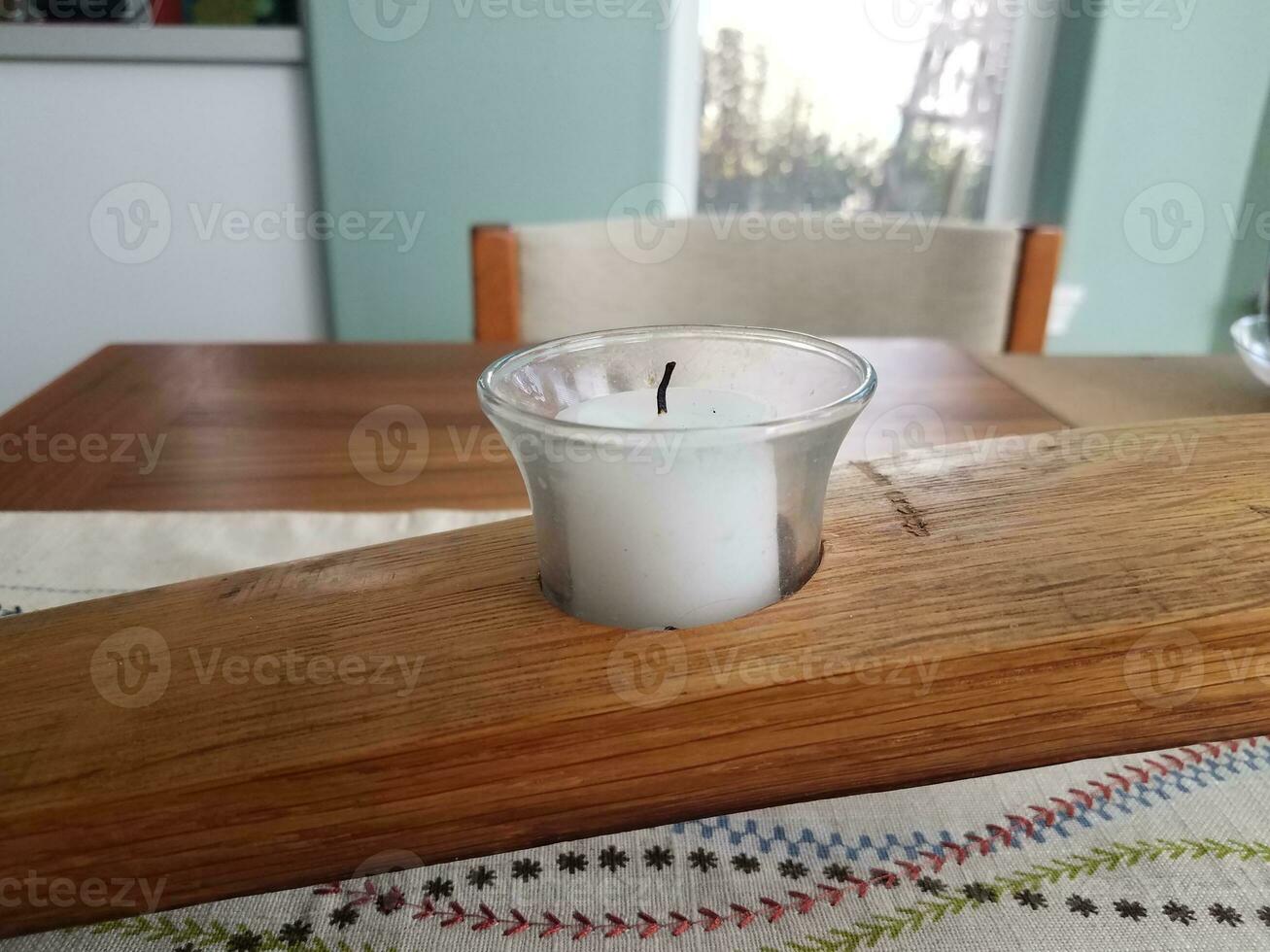 white candle in a wooden holder on a table photo