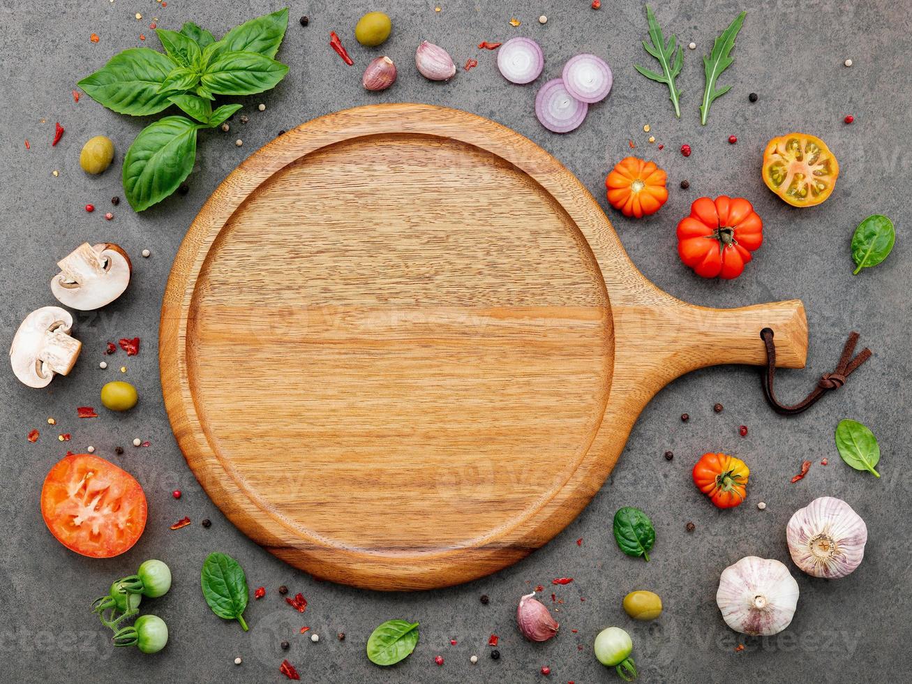 The ingredients for homemade pizza set up on dark stone background. photo