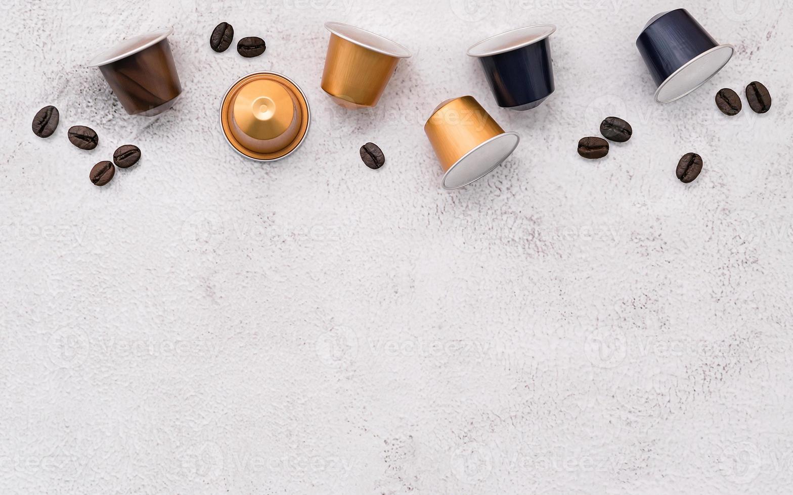 Dark roasted coffee beans and coffee capsule setup on white concrete background with copy space. photo