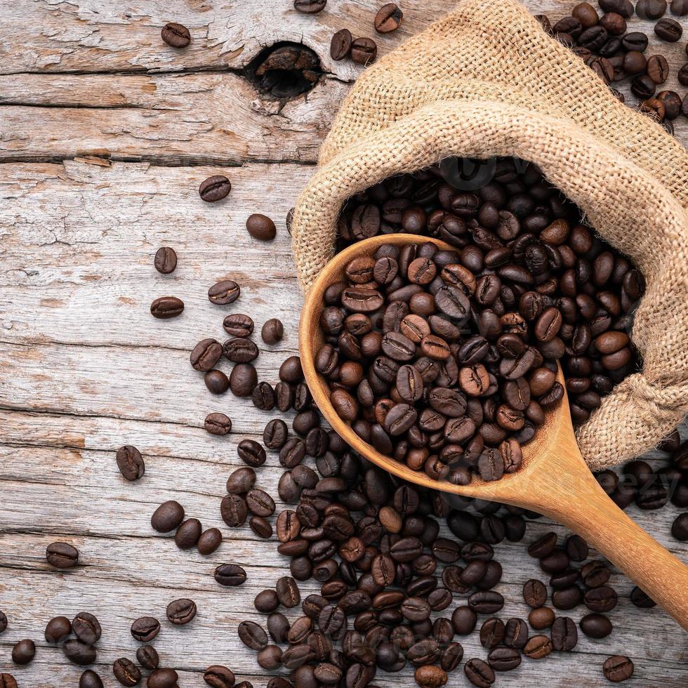 Background of dark roasted coffee beans with scoops setup on wooden background with copy space. photo