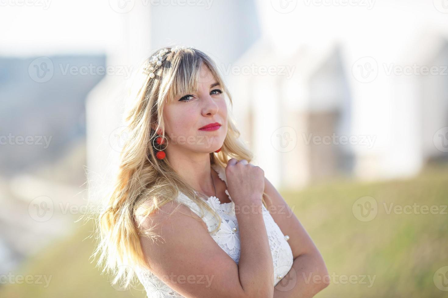 Outdoor close up portrait beautiful blonde girl with youth and skin care attractive looking at camera in white dress. Light key photo