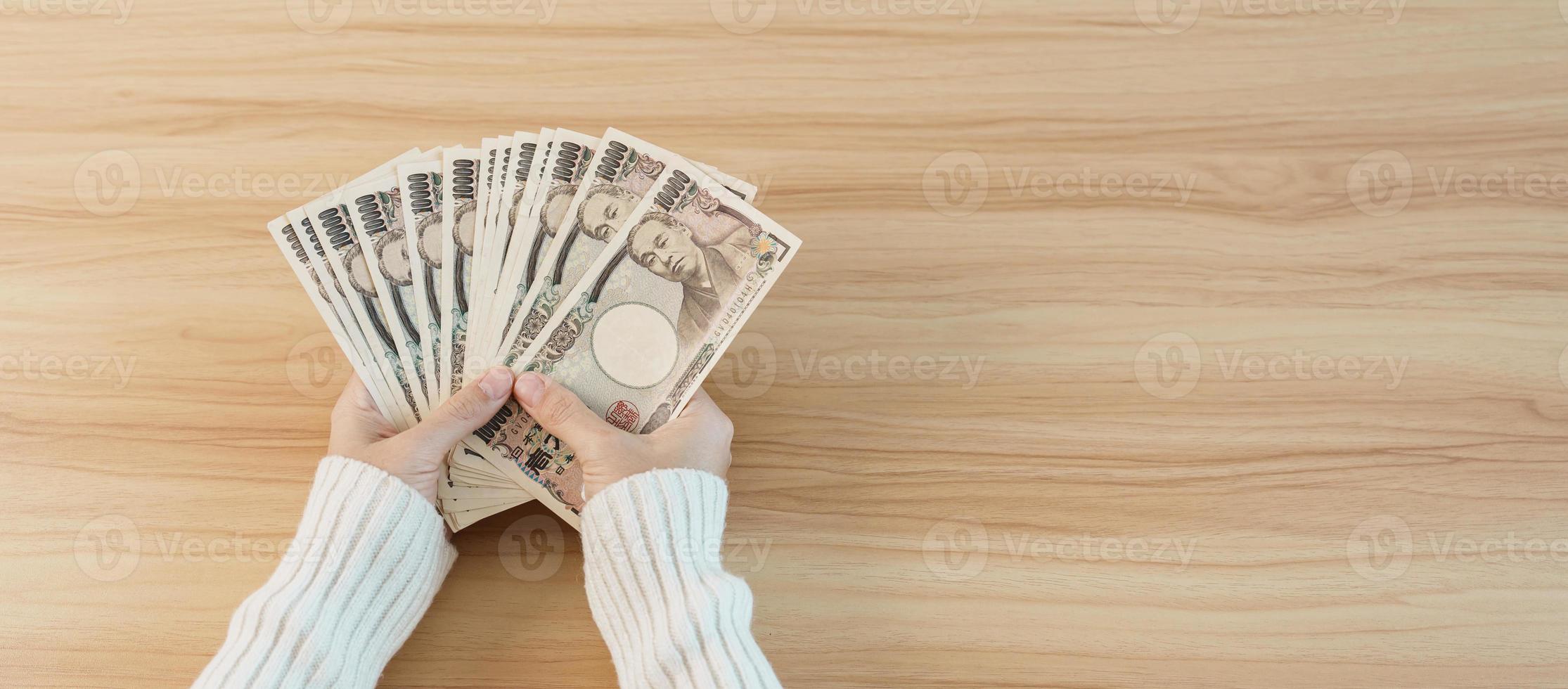 mano de mujer contando billetes de yenes japoneses sobre el fondo de la mesa. dinero de mil yenes. Japón efectivo, impuestos, economía de recesión, inflación, inversión, finanzas, ahorro, salarios y conceptos de pago foto