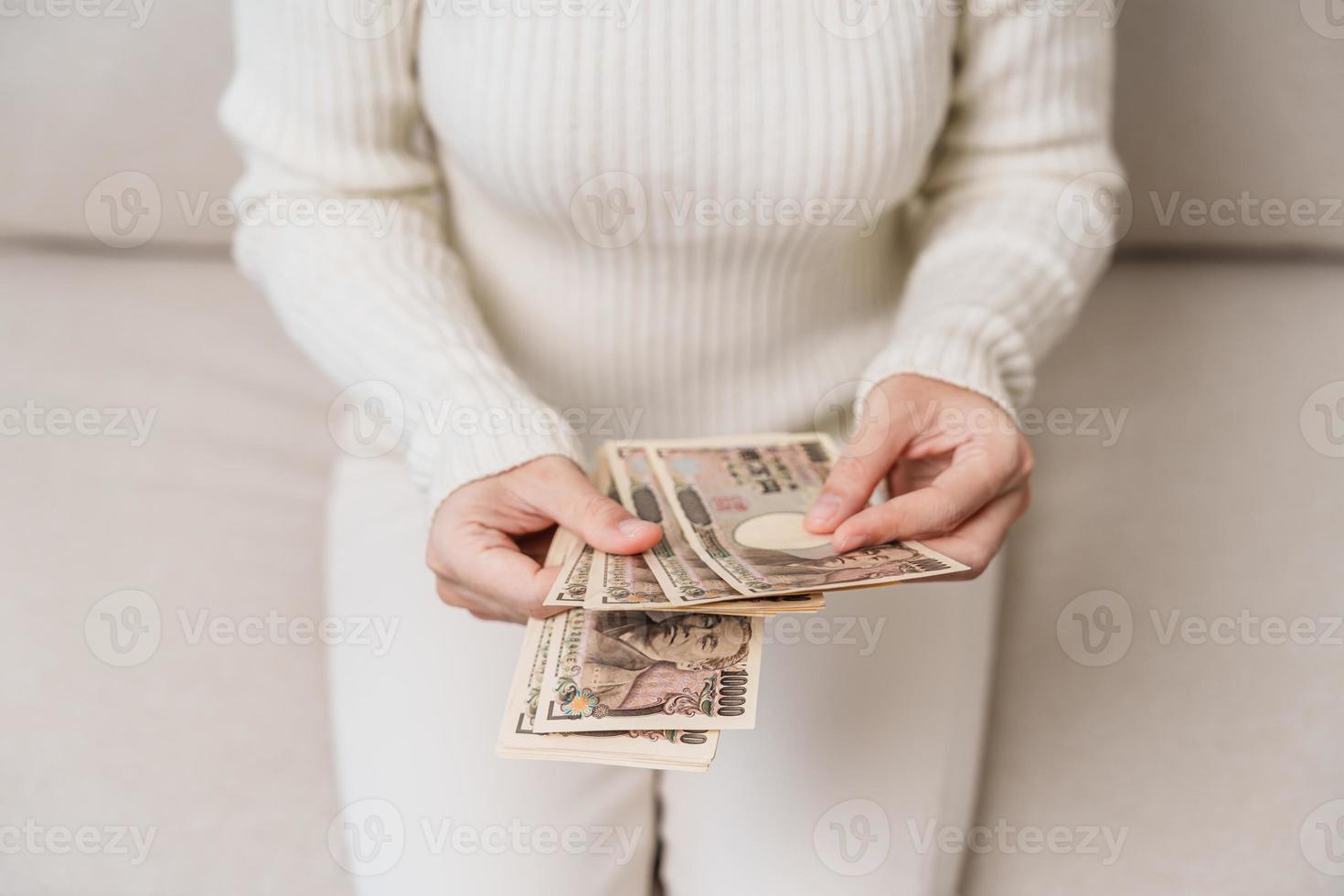 mano de mujer sosteniendo la pila de billetes de yen japonés. dinero de mil yenes. conceptos de pago en efectivo, impuestos, economía de recesión, inflación, inversión, finanzas y compras de japón foto