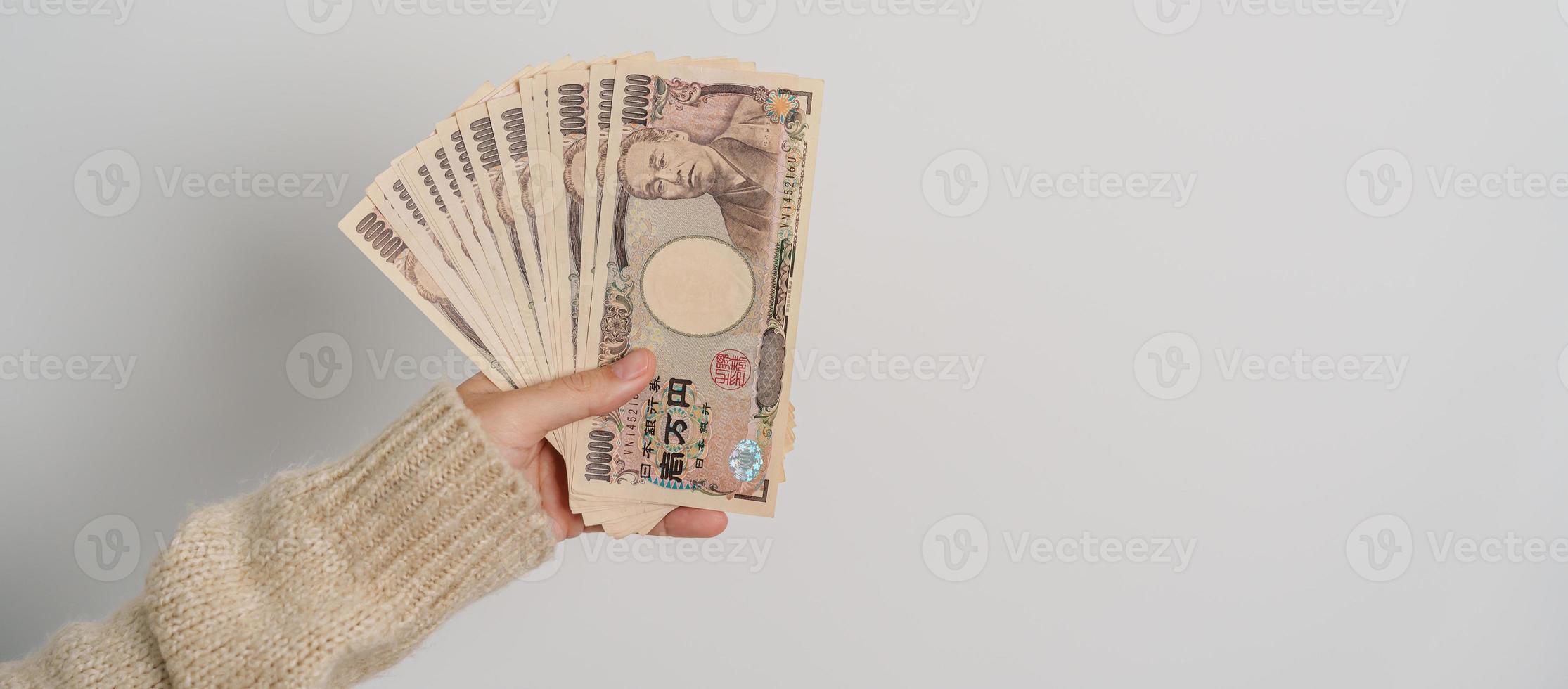 mano de mujer sosteniendo la pila de billetes de yen japonés. dinero de mil yenes. conceptos de pago en efectivo, impuestos, economía de recesión, inflación, inversión, finanzas y compras de japón foto