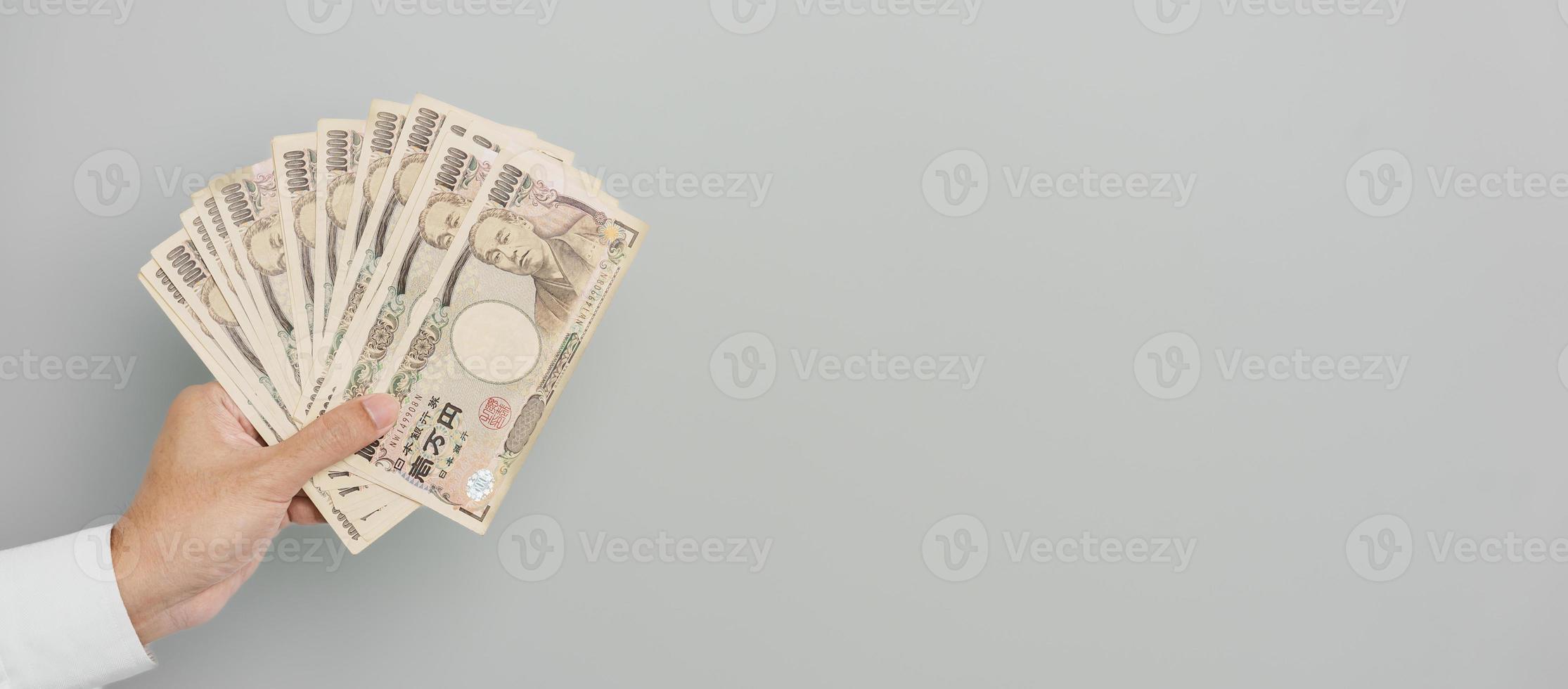 mano de hombre sosteniendo la pila de billetes de yen japonés. dinero de mil yenes. conceptos de pago en efectivo, impuestos, economía de recesión, inflación, inversión, finanzas y compras de japón foto