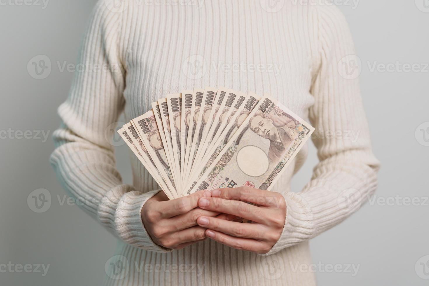 mano de mujer sosteniendo la pila de billetes de yen japonés. dinero de mil yenes. conceptos de pago en efectivo, impuestos, economía de recesión, inflación, inversión, finanzas y compras de japón foto