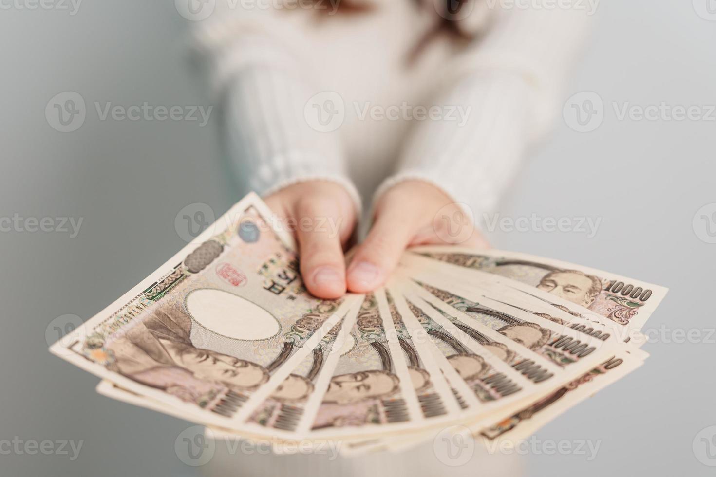 mano de mujer sosteniendo la pila de billetes de yen japonés. dinero de mil yenes. conceptos de pago en efectivo, impuestos, economía de recesión, inflación, inversión, finanzas y compras de japón foto