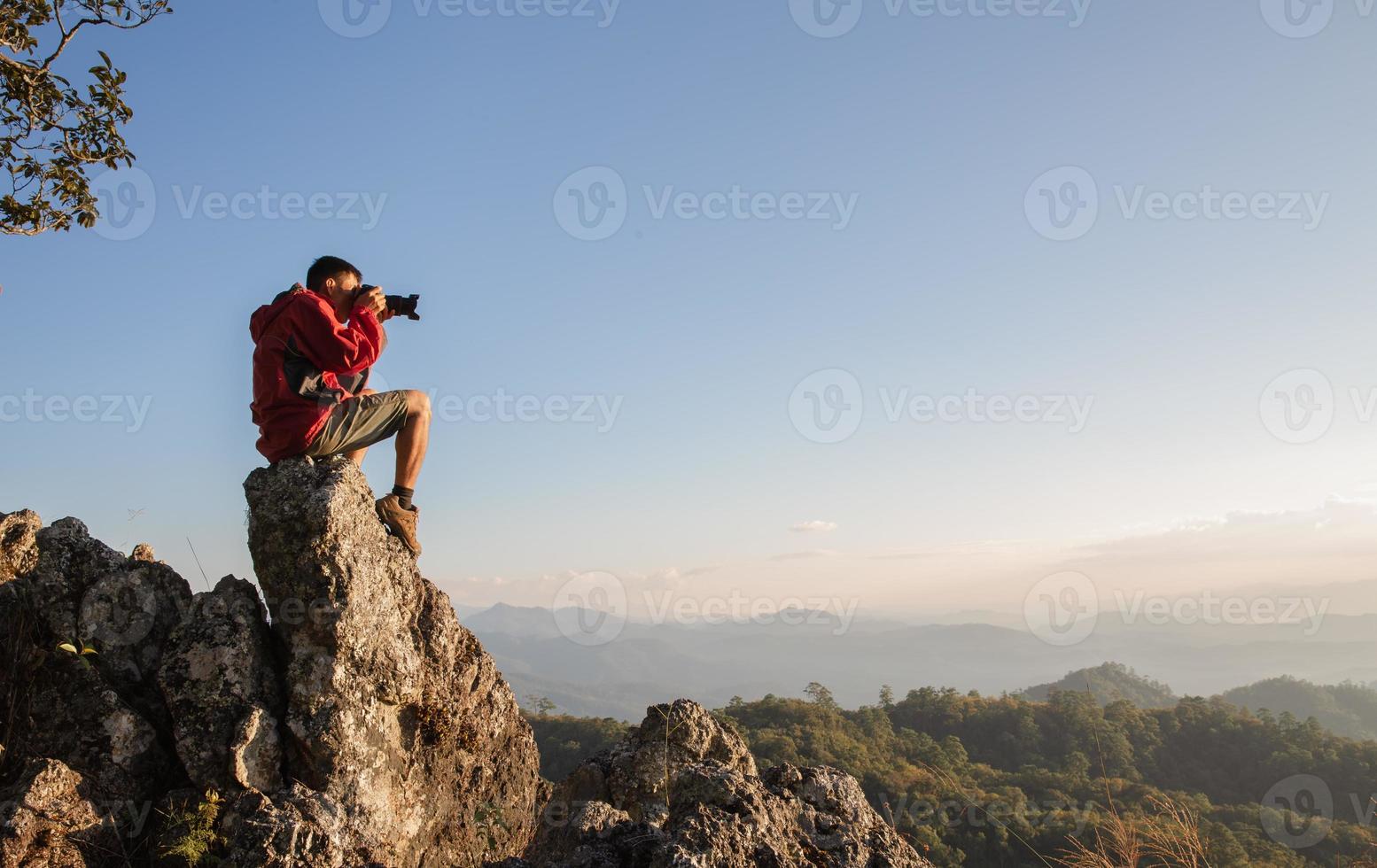 hombre sosteniendo una cámara en sus manos y haciendo fotos de las montañas durante la mañana de otoño, conceptos de senderismo y turismo