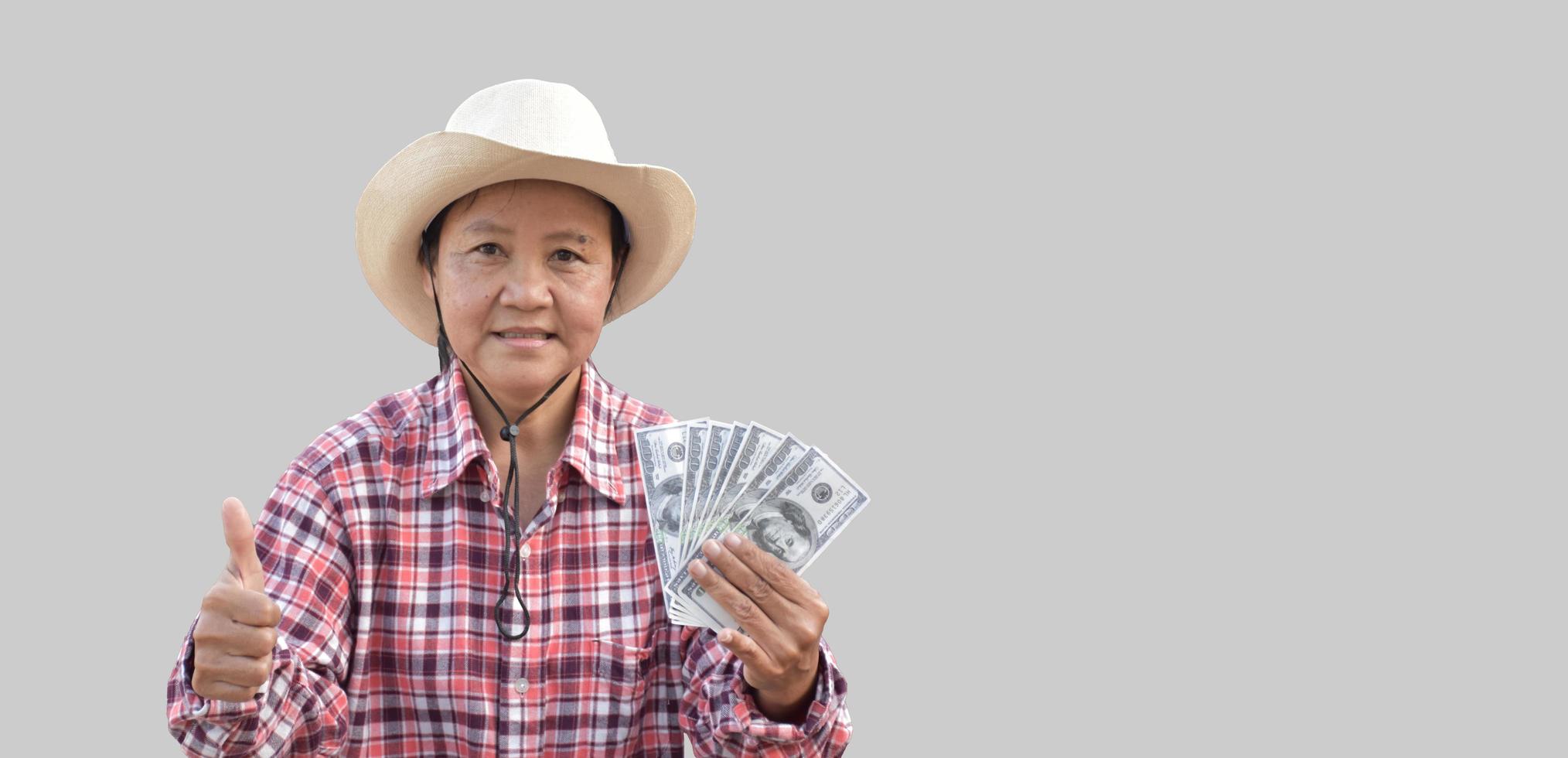 Isolated elderly asian woman holds US dollar bank notes in hand with beautiful smiling on her face happily with clipping paths. photo