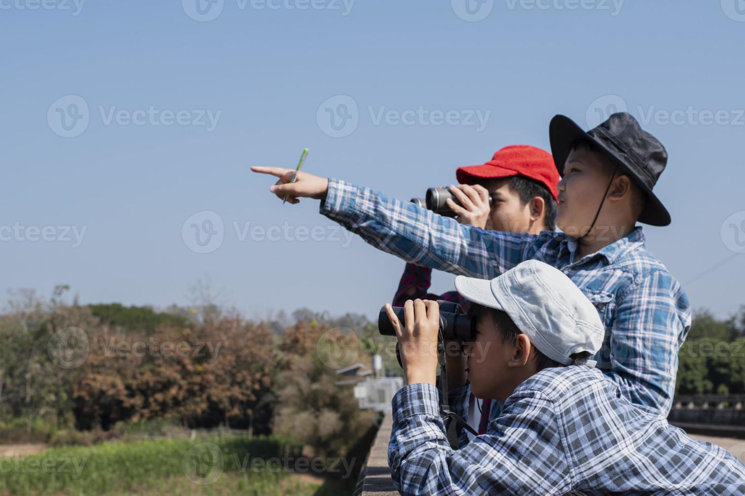 los niños asiáticos están usando binoculares para observar aves en el bosque tropical durante el campamento de verano, idea para aprender criaturas y animales salvajes e insectos fuera del aula. foto