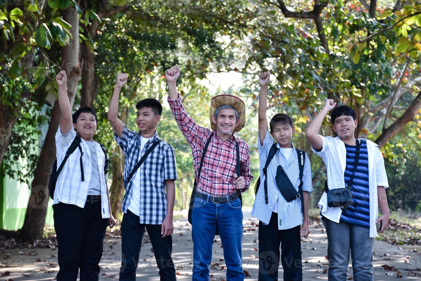 Soft focus of elderly asian musician teacher standing together with his students during taking outdoor music lesson, soft and selective focus, adult helps students about school project work concept. photo