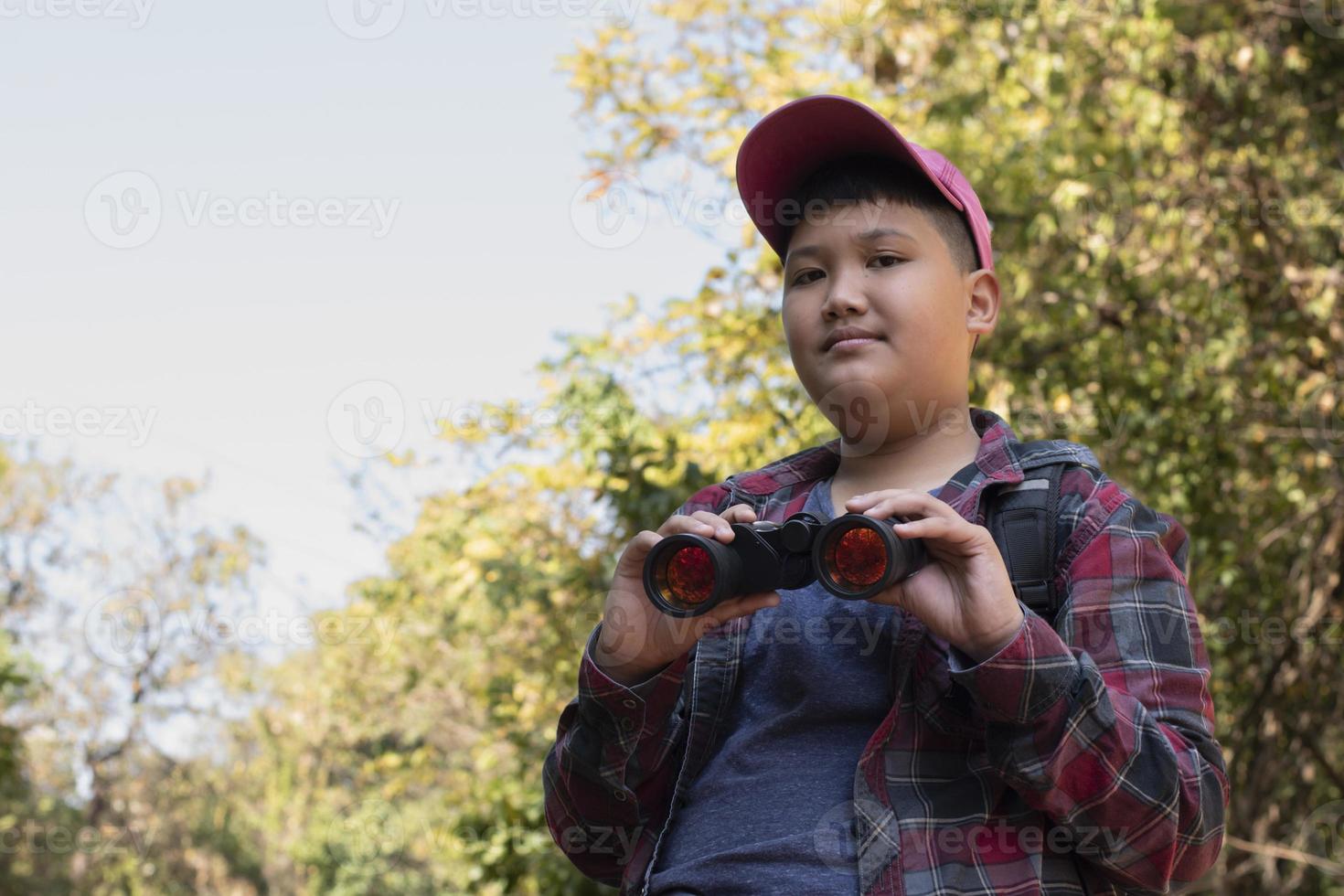 Asian boys are using binoculars to do the birds' watching in tropical forest during summer camp, idea for learning creatures and wildlife animals and insects outside the classroom. photo