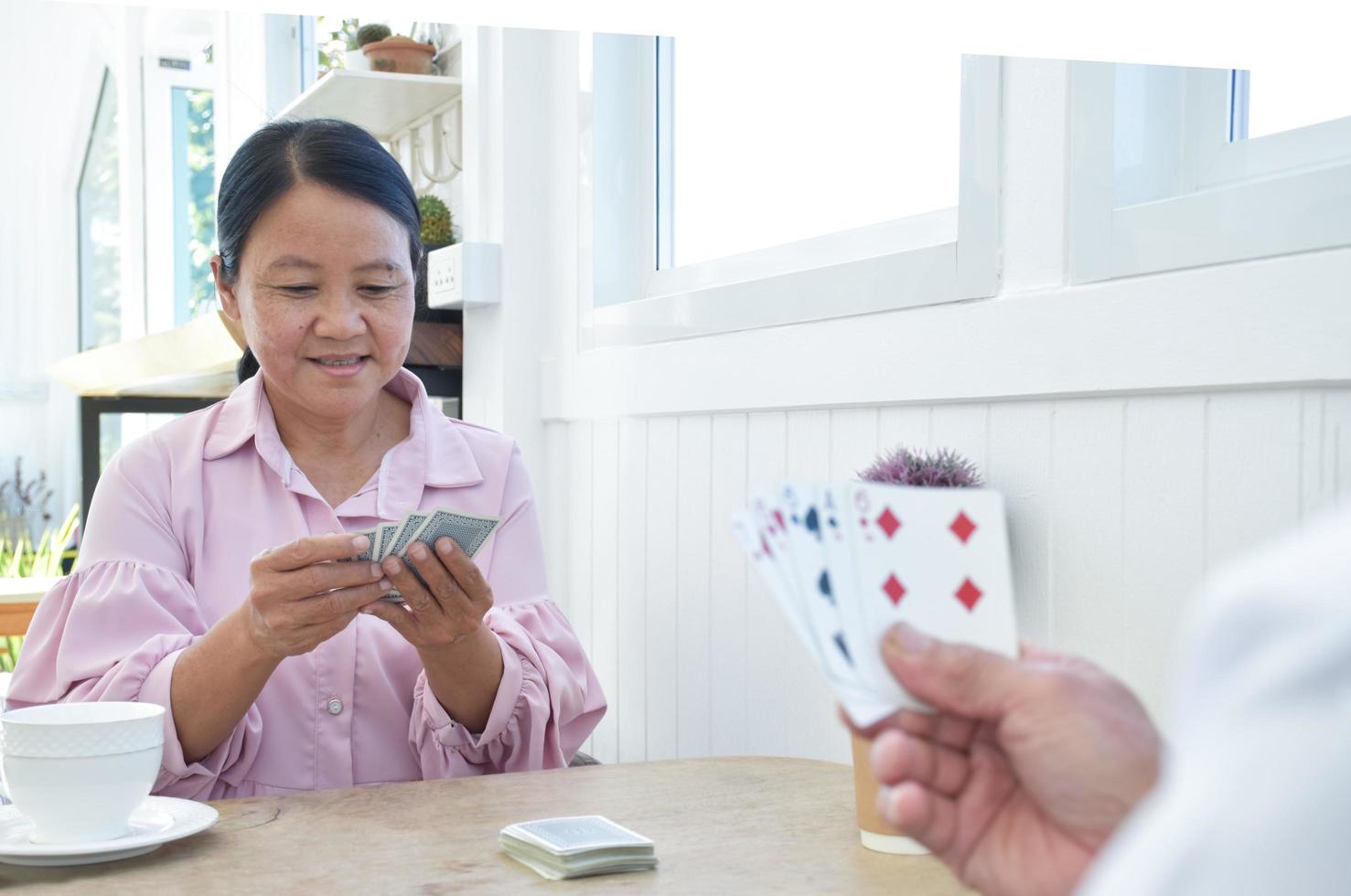 Card playing of elderly people at home in their freetimes, recreation and happiness of elderly people concept. photo