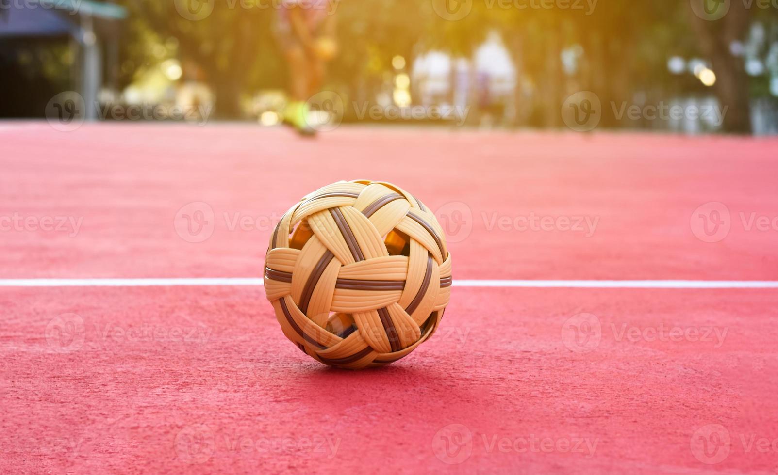 Sepak takraw ball on red floor of outdoor court, blurred background, recreactional activity and outdoor sports in Southeast asian countries concept. photo