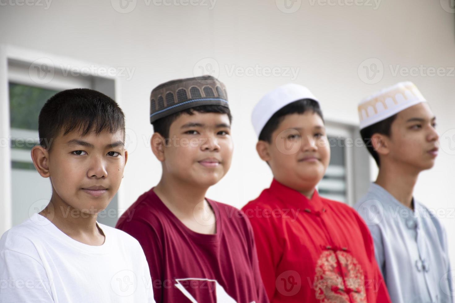 Portrait asian muslim or islamic boys sitting with muslim boys in a row to pray or to do the religious activity, soft and selective focus. photo