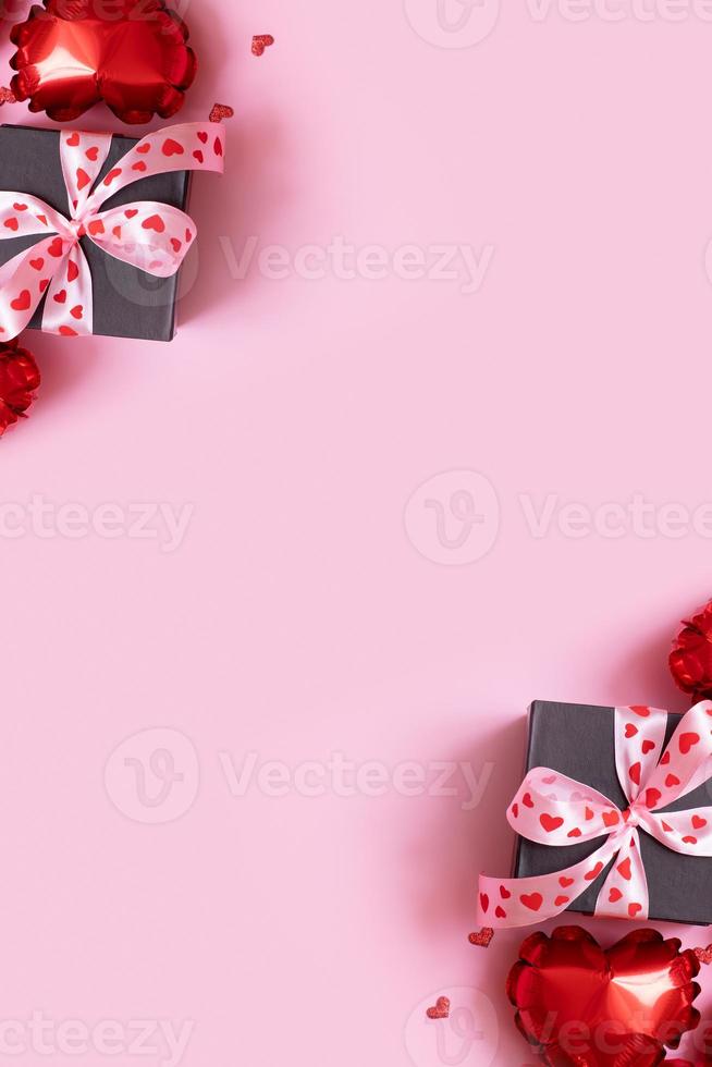 Present gift box with bow and heart shape baloons on pink background. Valentines Day background with copy space photo