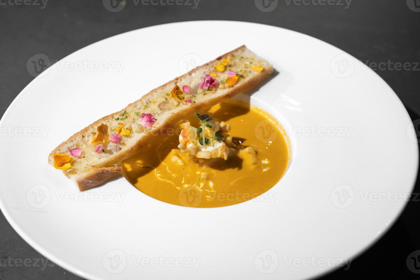 pan de ajo con sopa cremosa de tomyamkung en un plato blanco con luz de estudio, decorado con pétalos de flores. foto