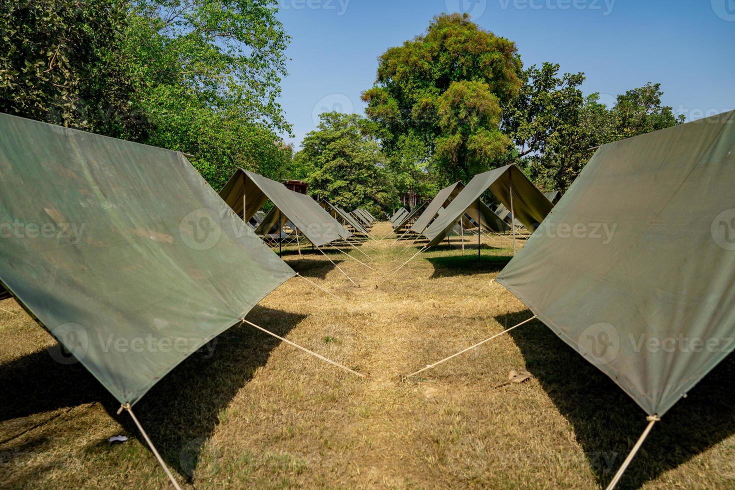 The simple and normal empty Canvas Tents in the row and column on the grass field at outdoor field in afternoon time. photo