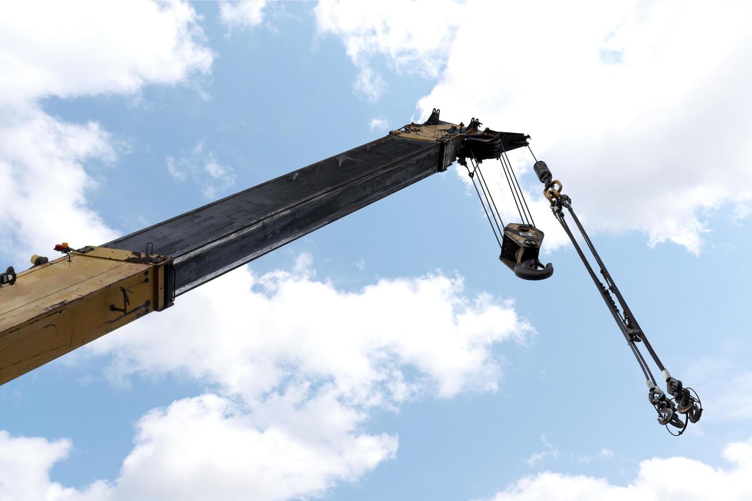 Yellow crane boom with hooks and blue sky background photo