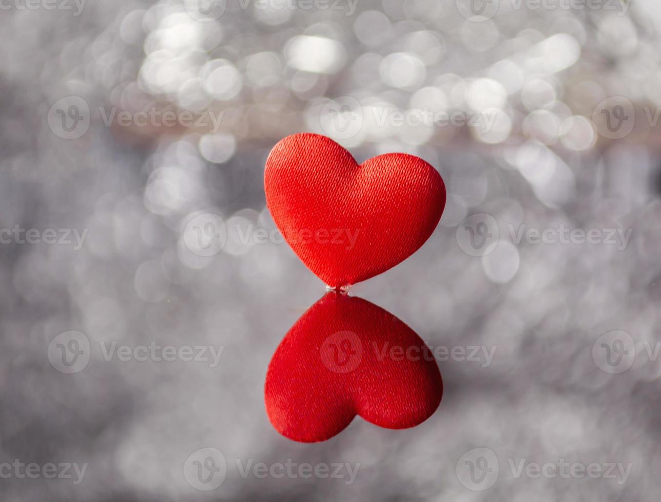 red heart on silver shiny background with reflection, valentine's concept , copy space for text and designs photo
