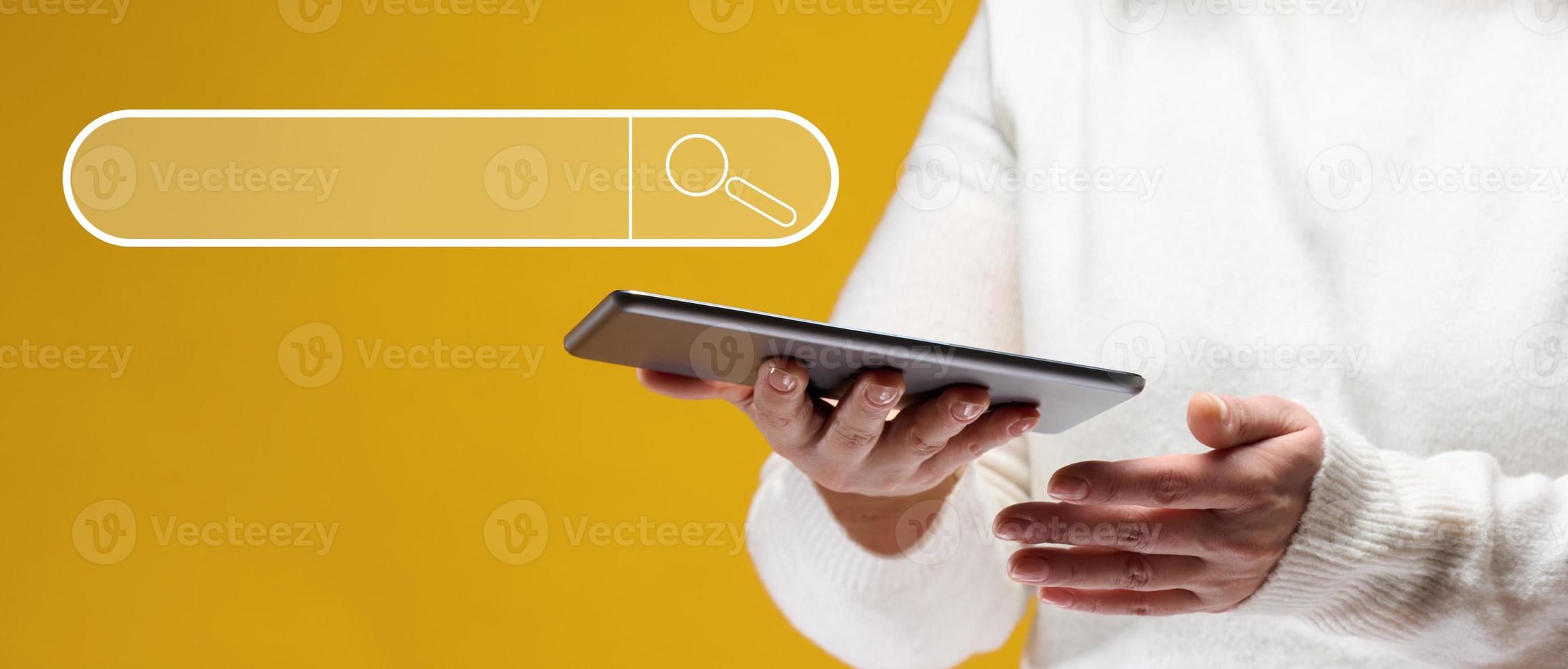 A woman is holding an electronic tablet on a yellow background. Search for information on the Internet, free access to the network photo