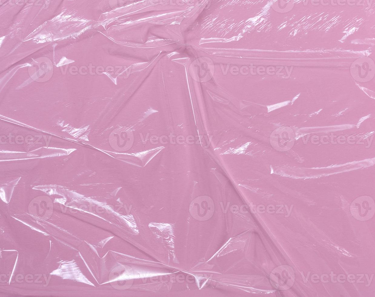 Texture of crumpled transparent polyethylene on a pink background, full frame. photo