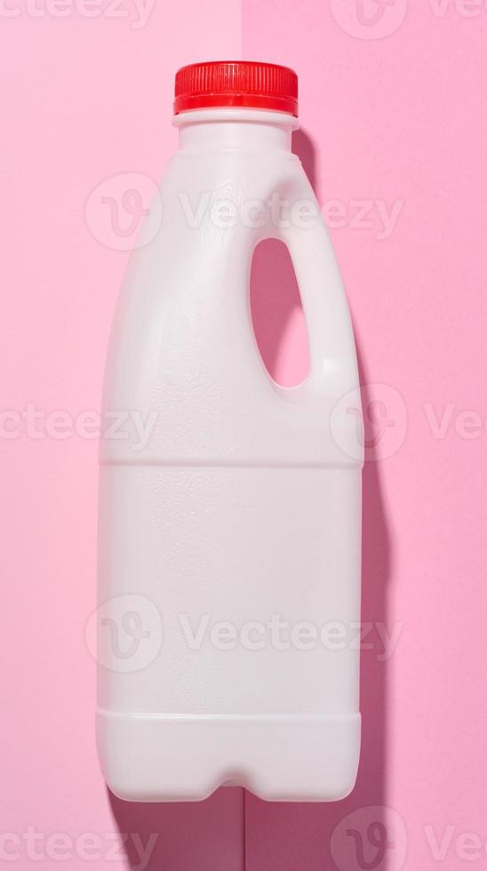 White plastic bottle for milk and dairy products on a pink background photo