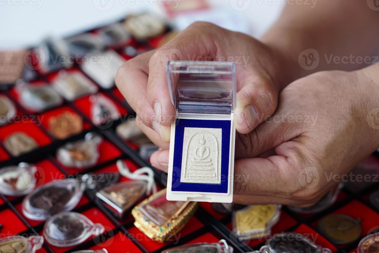 Closeup hand holds Thai Buddha amulet from amulet collection. Concept, faith and belief for Buddhist for holy and luck. Colleting amulet as hobbies, exchange, selling or buying photo