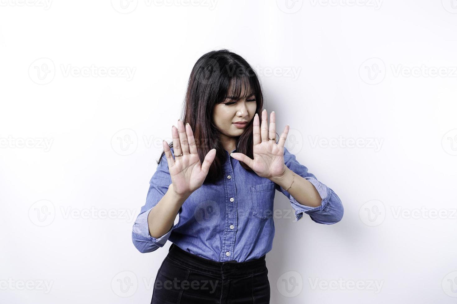 Young Asian woman isolated on white background, looks depressed, face covered by fingers frightened and nervous. photo