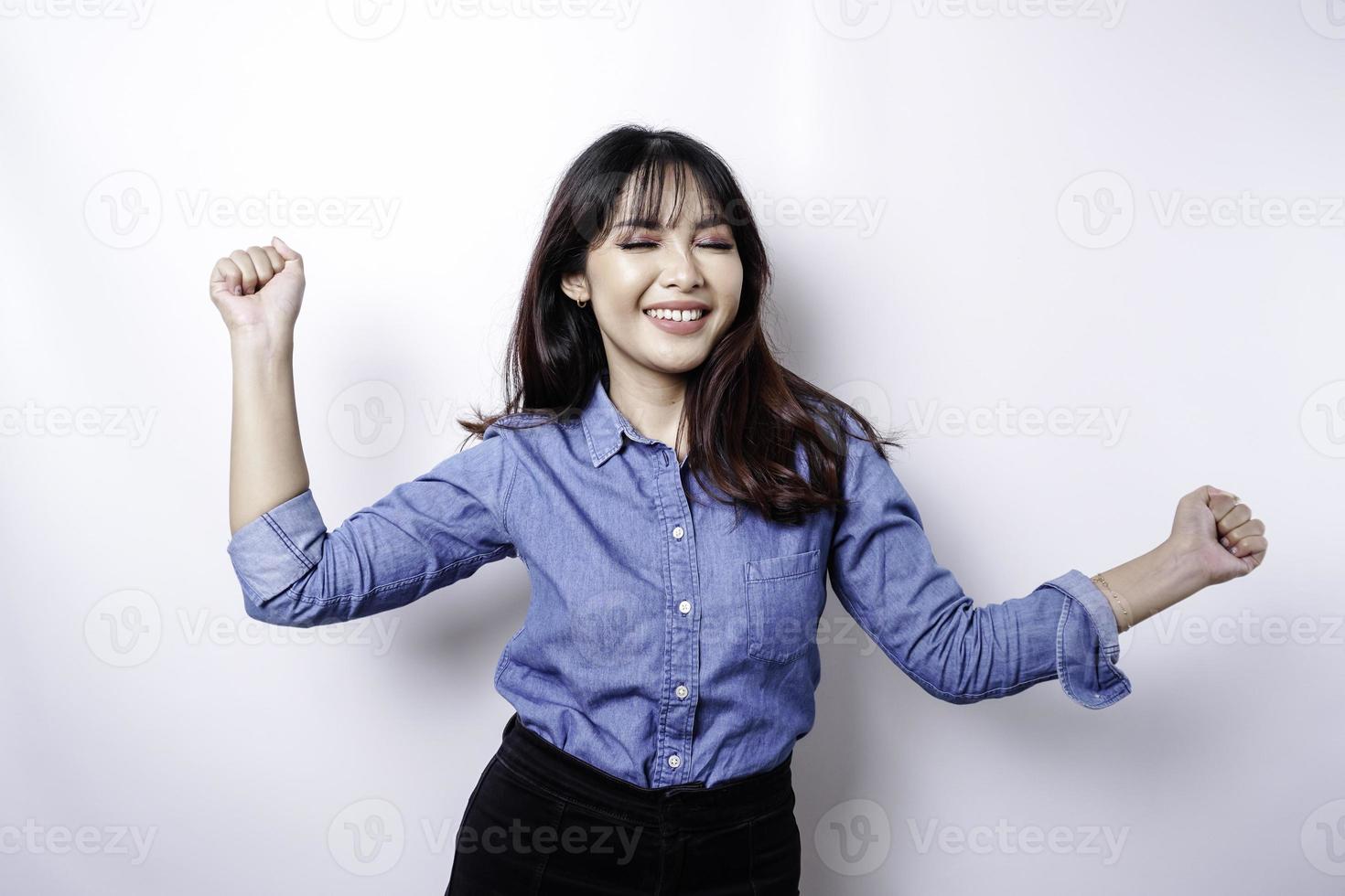 una joven asiática con una expresión feliz y exitosa que usa una camisa azul aislada de fondo blanco foto