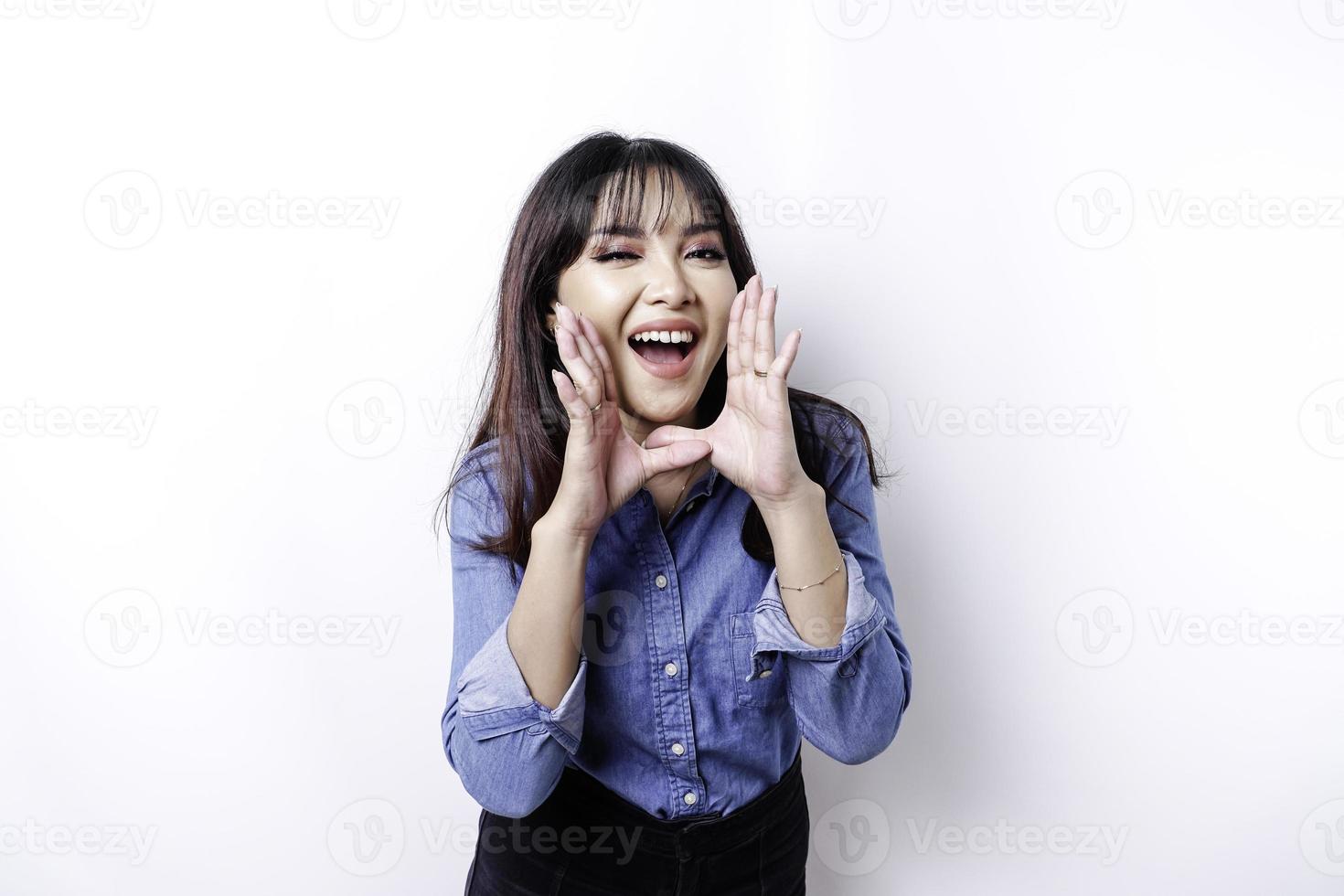 joven mujer hermosa con una camisa azul gritando y gritando fuerte con una mano en la boca. concepto de comunicación foto