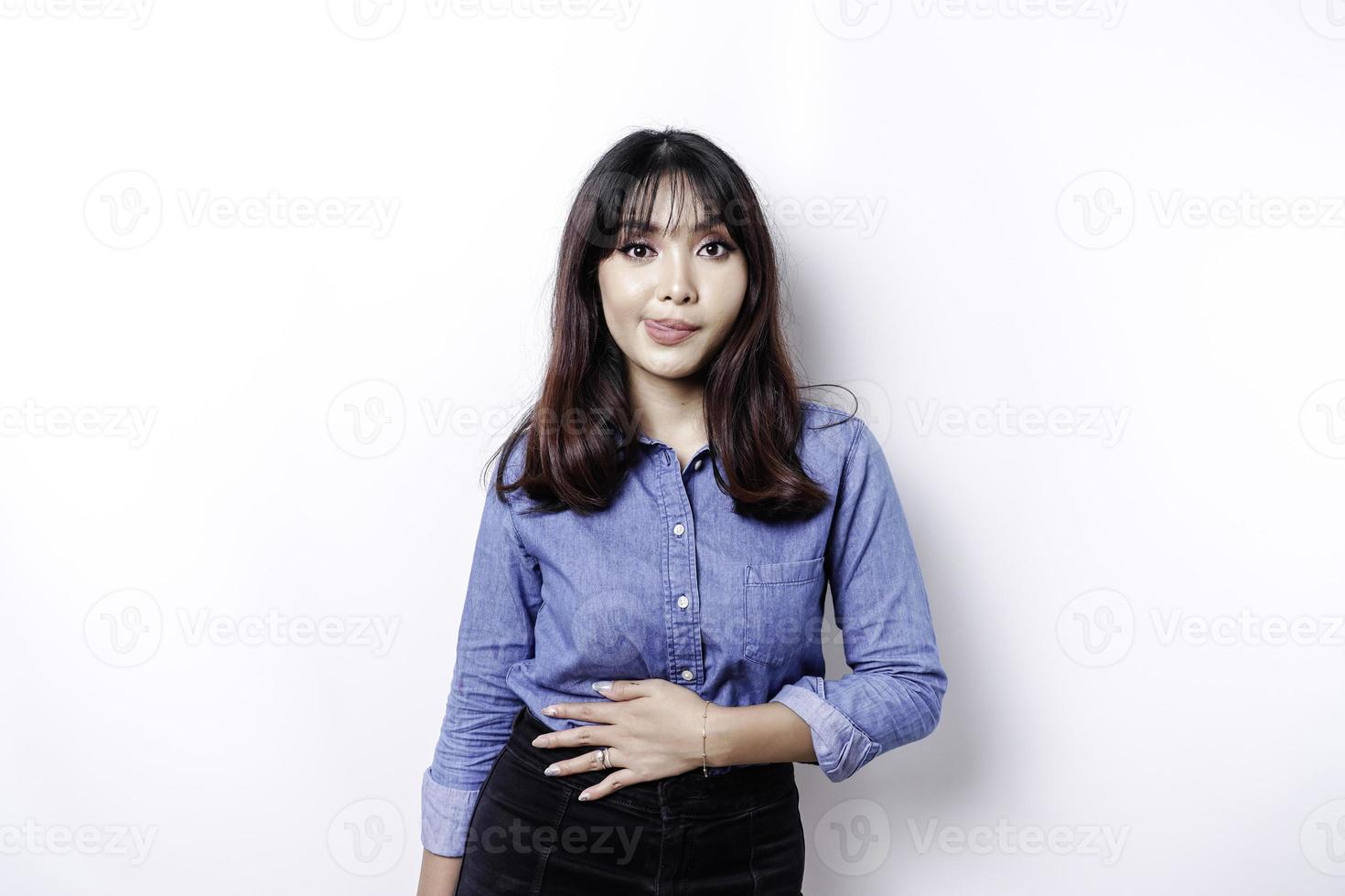 An Asian woman is hungry and touching her belly while looking aside thinking what to eat photo