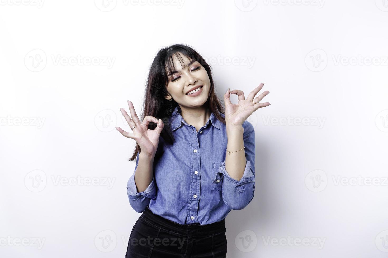 Excited Asian woman giving an OK hand gesture isolated by a white background photo