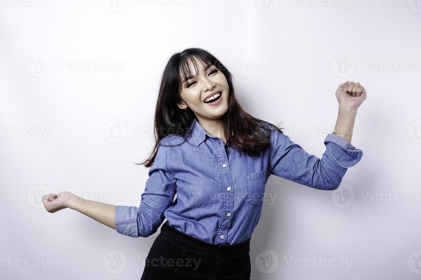 una joven asiática con una expresión feliz y exitosa que usa una camisa azul aislada de fondo blanco foto