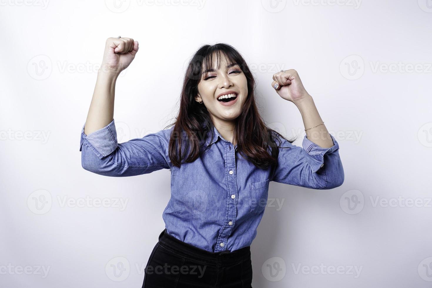 A young Asian woman with a happy successful expression wearing blue shirt isolated by white background photo