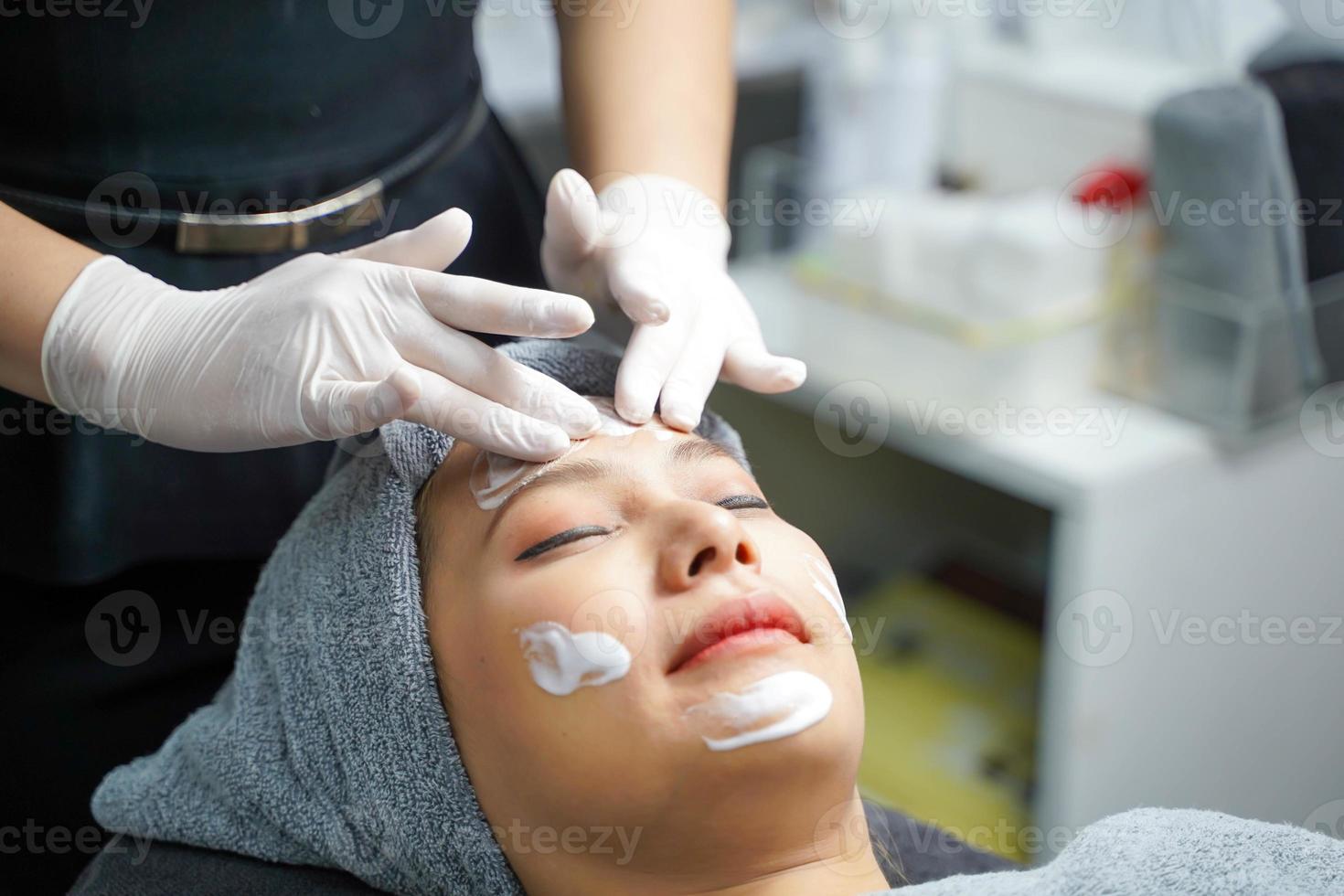 mujer joven belleza en toalla haciendo masaje facial con exfoliante facial orgánico. foto