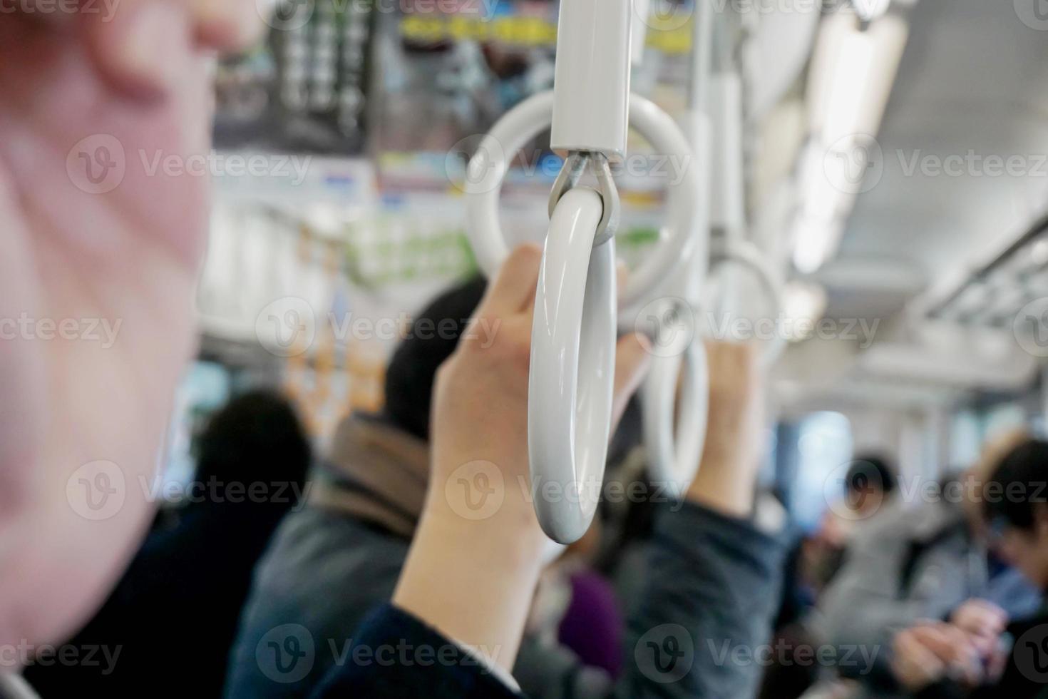 Closeup hand of human holding handle loop in a subway morning and blurry background. photo