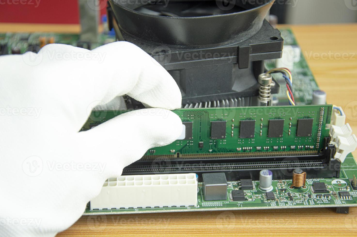 Side view of a technician clearing the RAM of a computer motherboard. photo