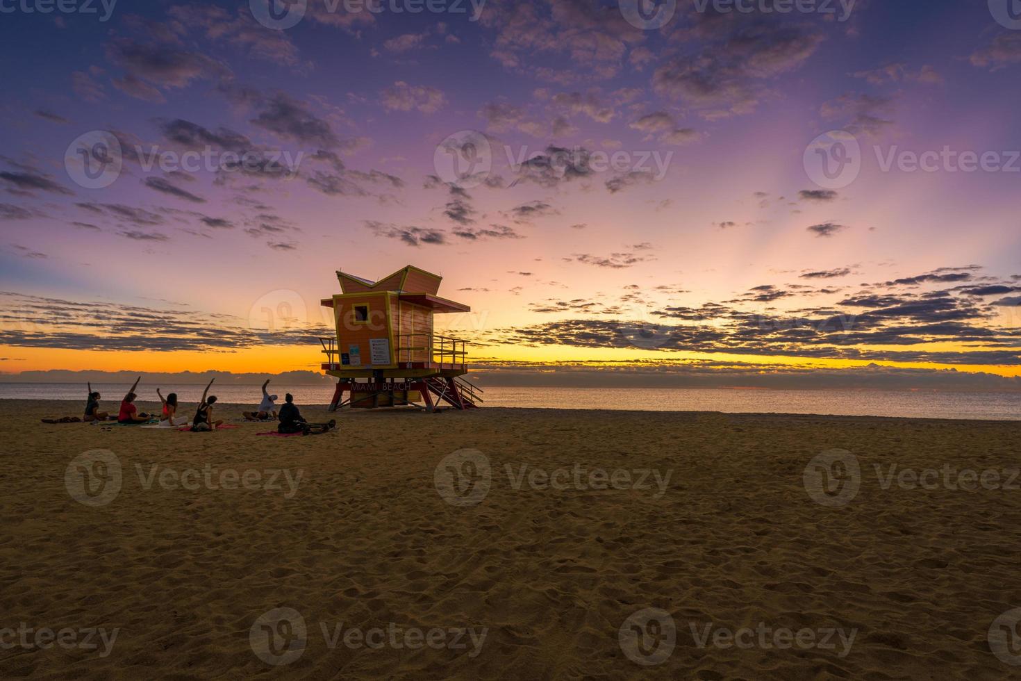 Sunrise at one of the famous lift guard houses in Miami Beach, Florida, USA with a Yoga team doing exercises photo