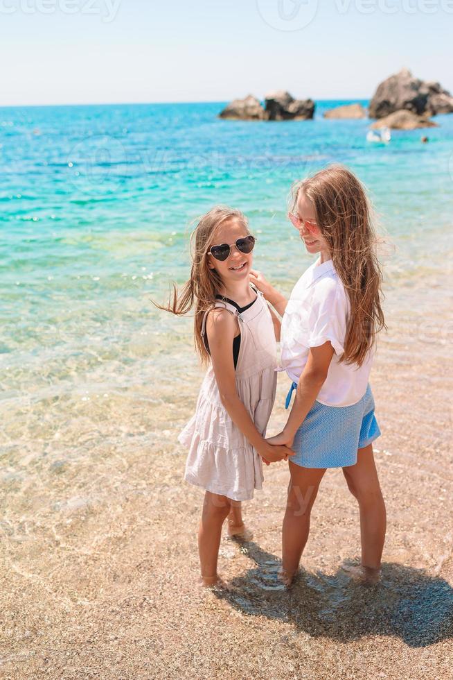 Little happy funny girls have a lot of fun at tropical beach playing together photo