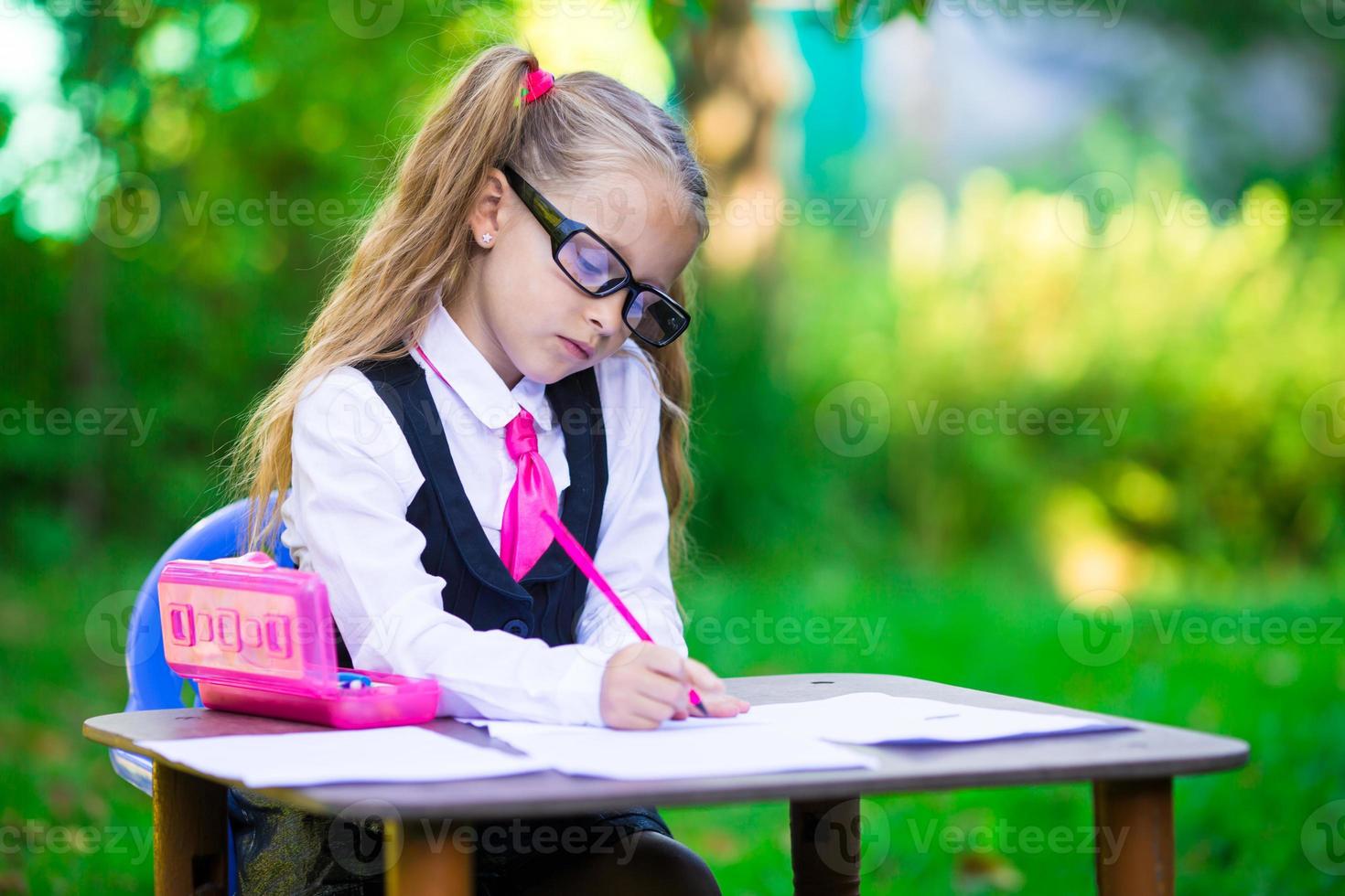 adorable colegiala en el escritorio con notas y lápices al aire libre. De vuelta a la escuela. foto