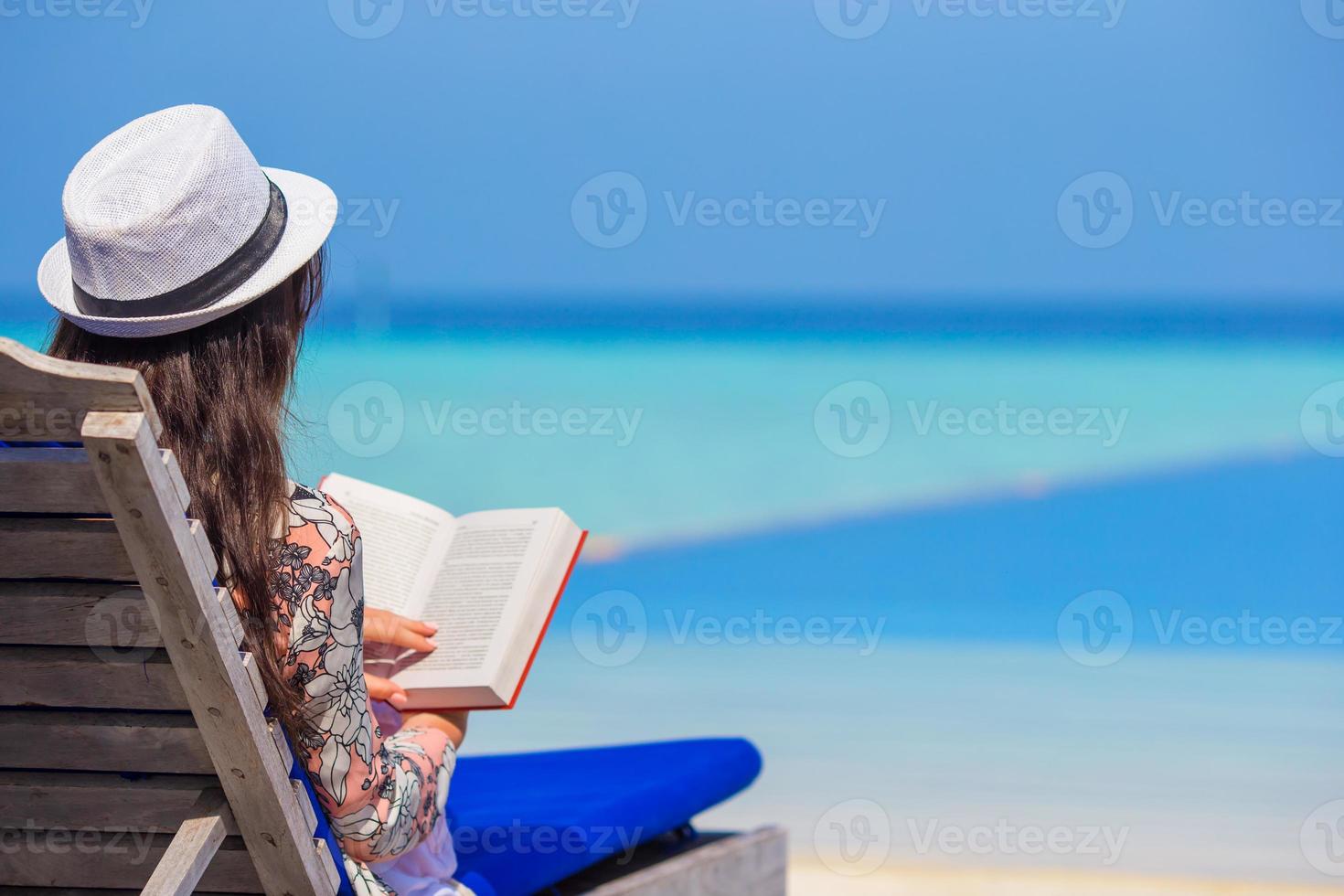 Young woman reading book during tropical white beach photo