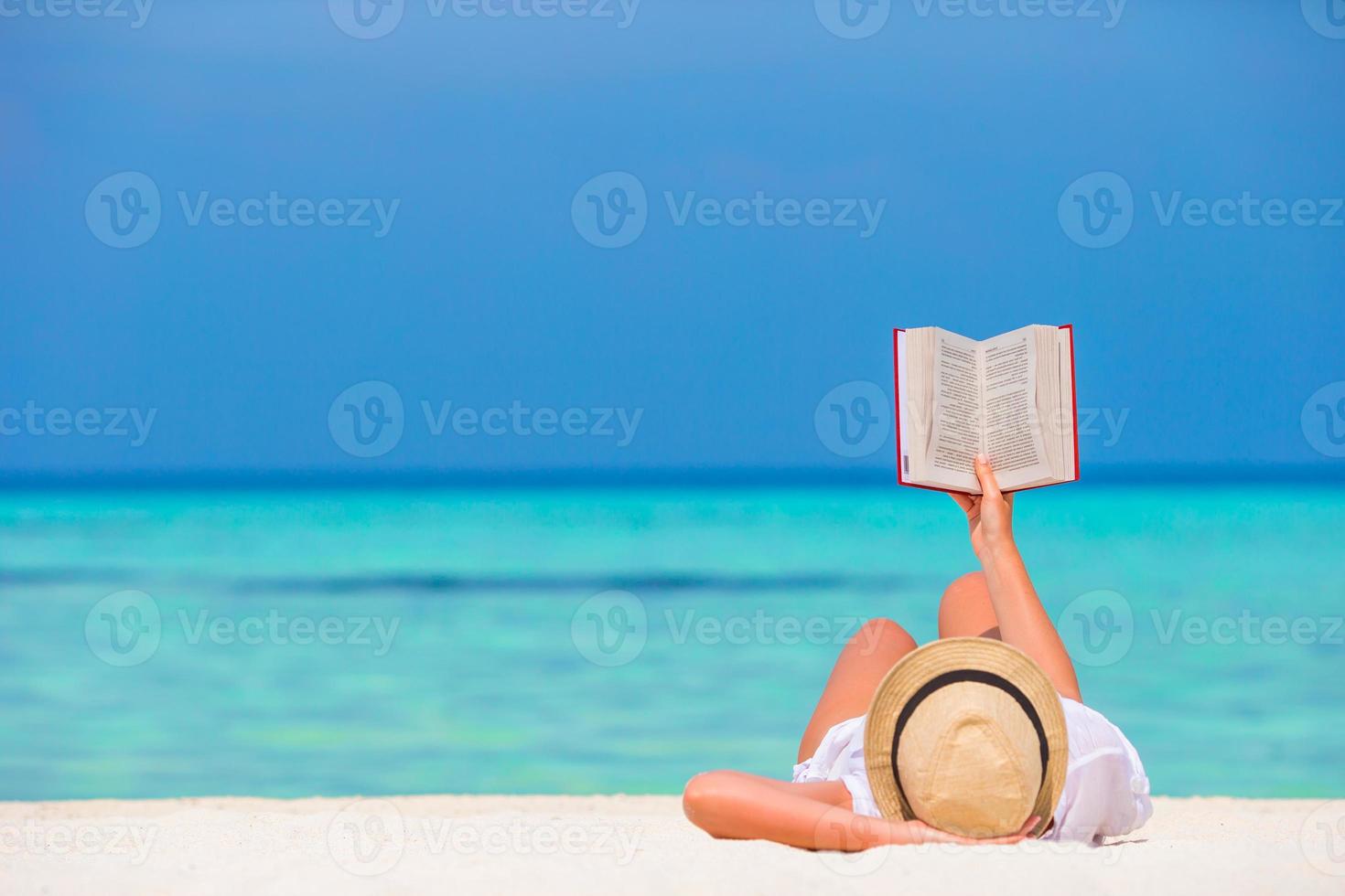 Happy girl reading during tropical white beach photo