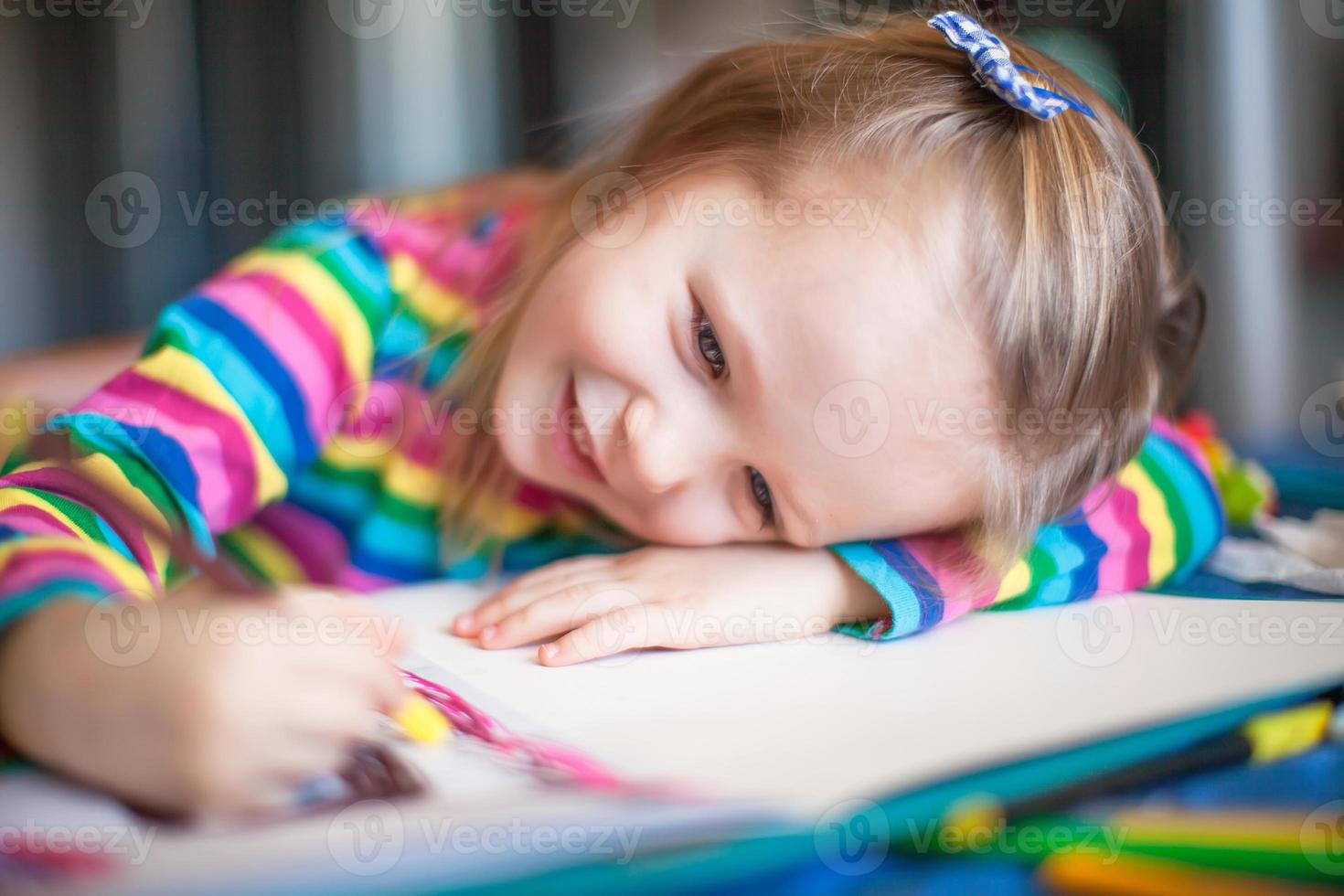 Little cute girl painting with pencils while sitting at her table photo